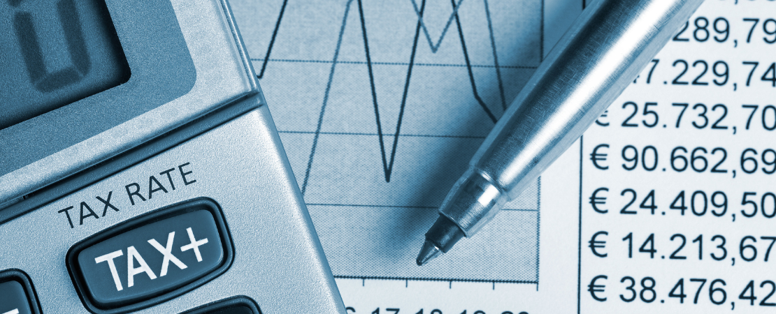 Taschenrechner mit 'TAX'-Anzeige, Finanzdiagramme, Euro-Zahlen und ein Stift auf einem Schreibtisch